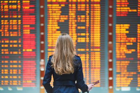 woman standing in front of flight cancellation board