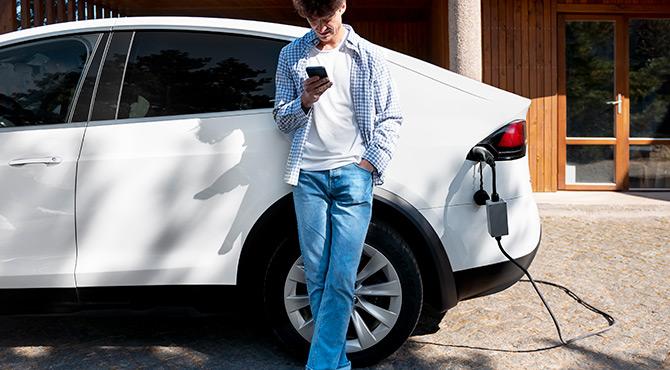 Man standing with electric car Tesla