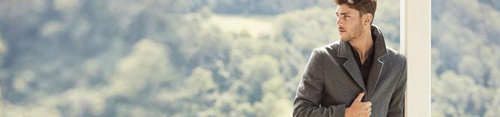 Man leaning on pole in front of hilly scenery